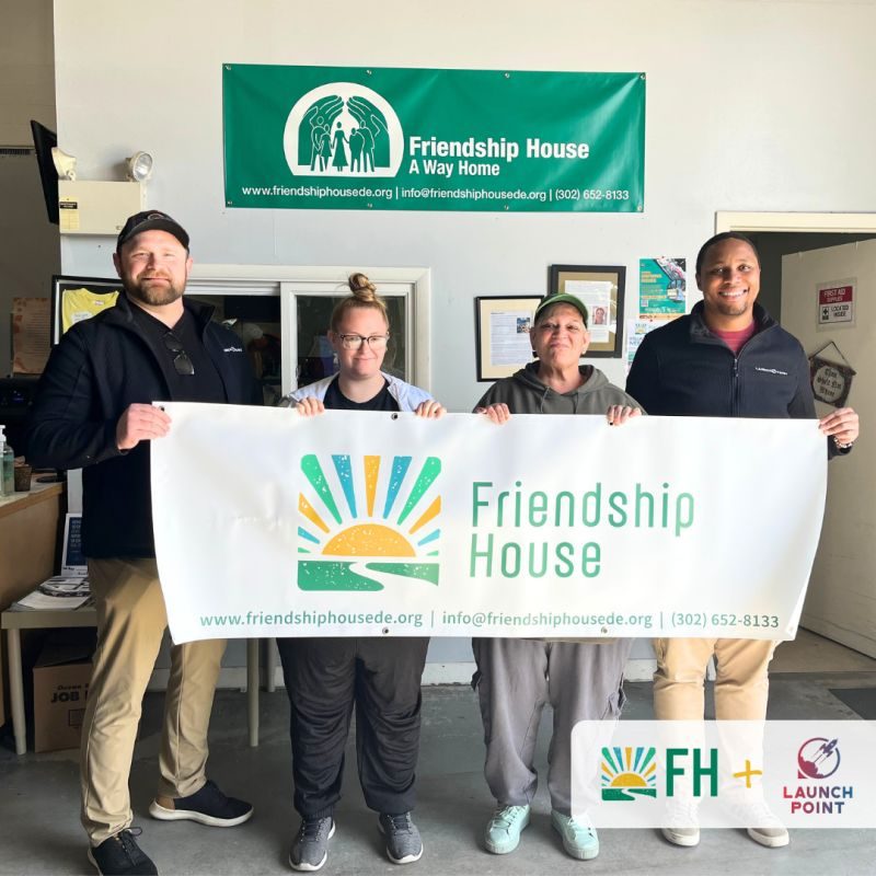 Friendship House and Launch Point Labs team holding the Friendship House banner